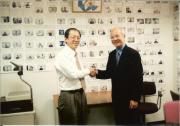 2000年SIAで講演後す握手するMealy Truong氏とSIA代表佐々木：バックは600回を超えるSIA国際フォーラムの各国講演者の写真
